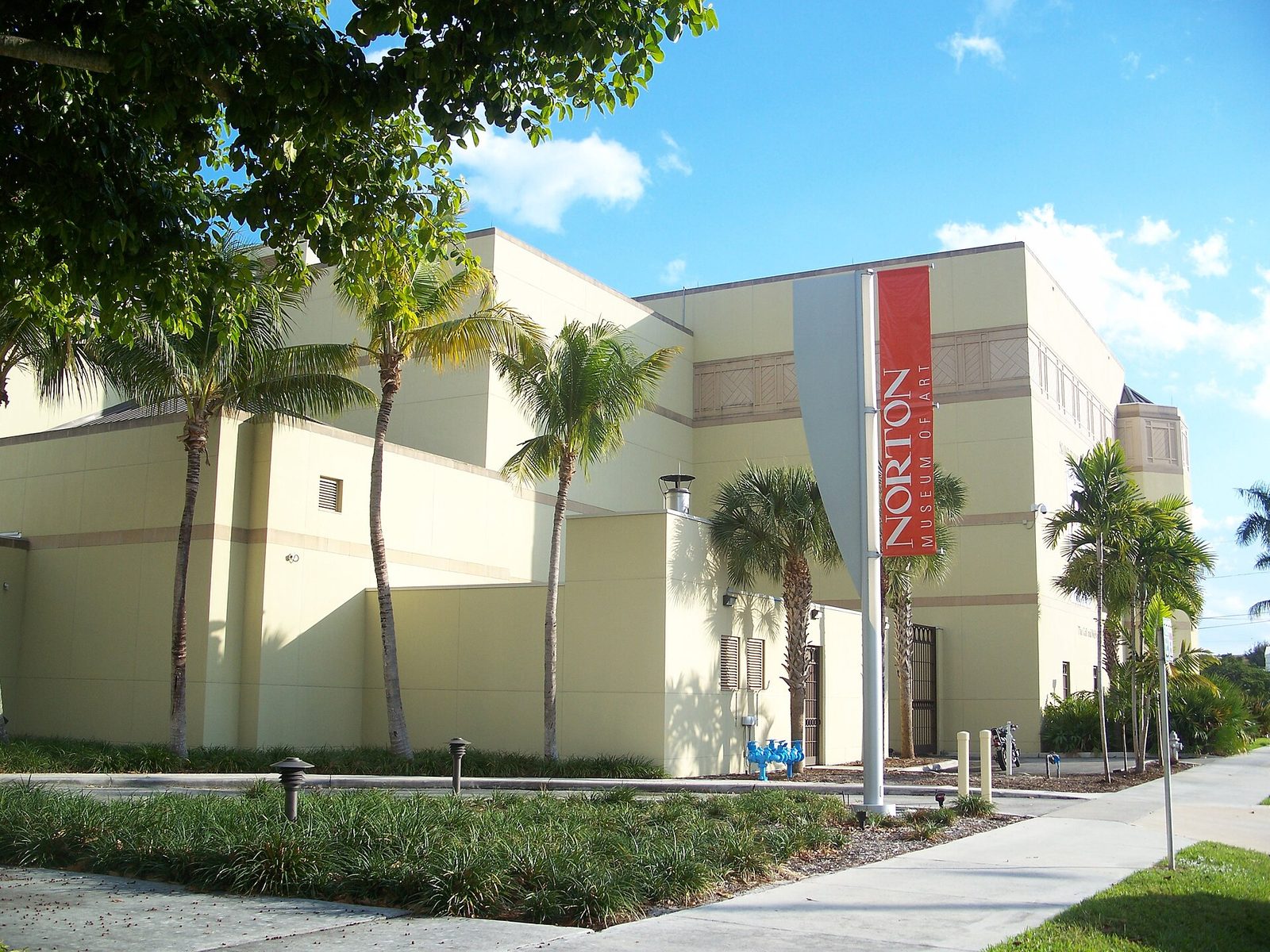 The Norton Museum of Art building in West Palm Beach, Florida, with its red museum banner and palm trees