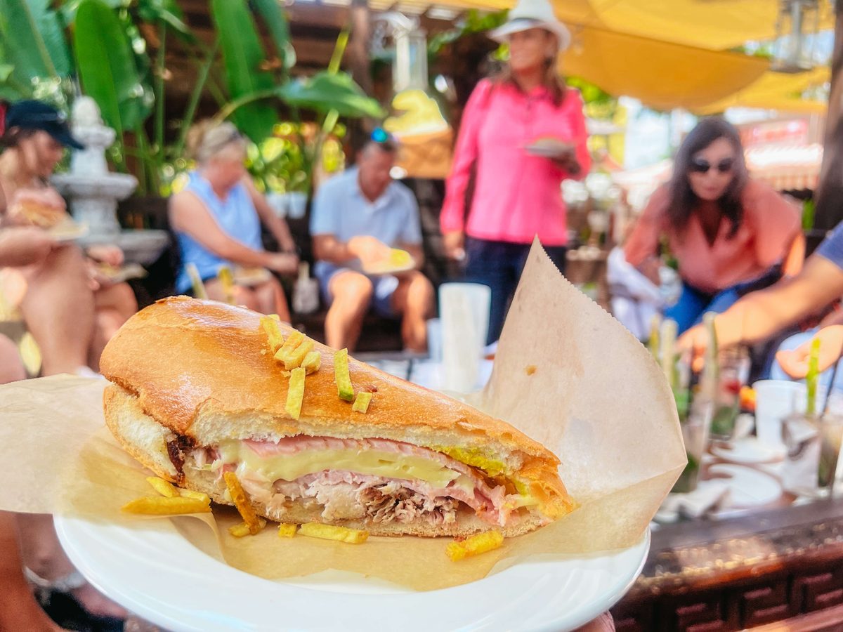 A Cuban sandwich served on the Little Havana food tour, tour group tasting behind