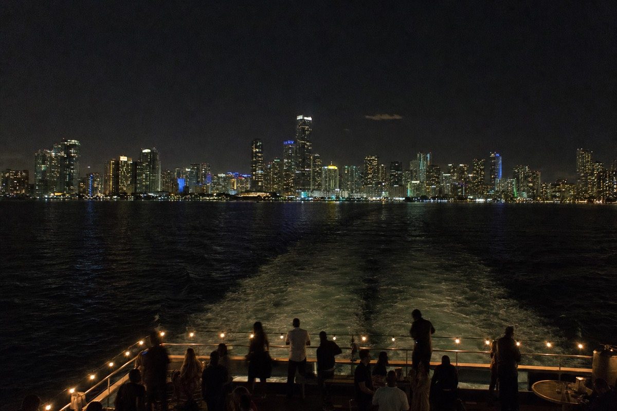 Passengers on a night cruise looking at the lit-up downtown Miami skyline