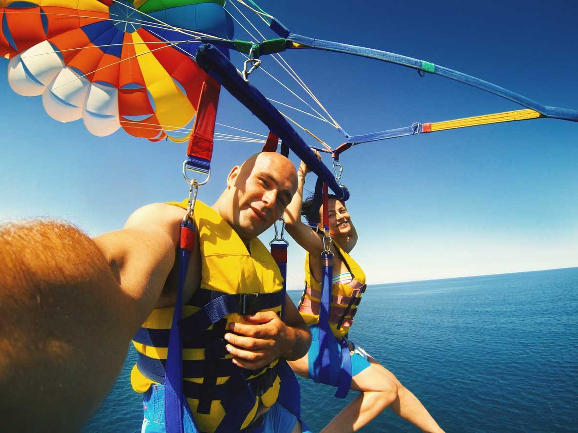 A couple parasailing tandem high above the turquoise water off Miami Beach